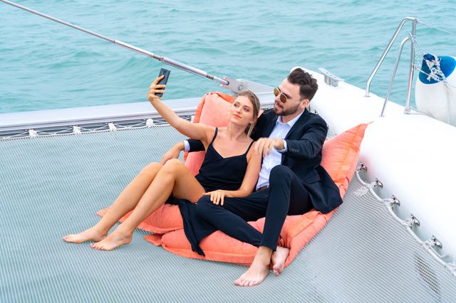 A couple snuggling on a yacht take a selfie.